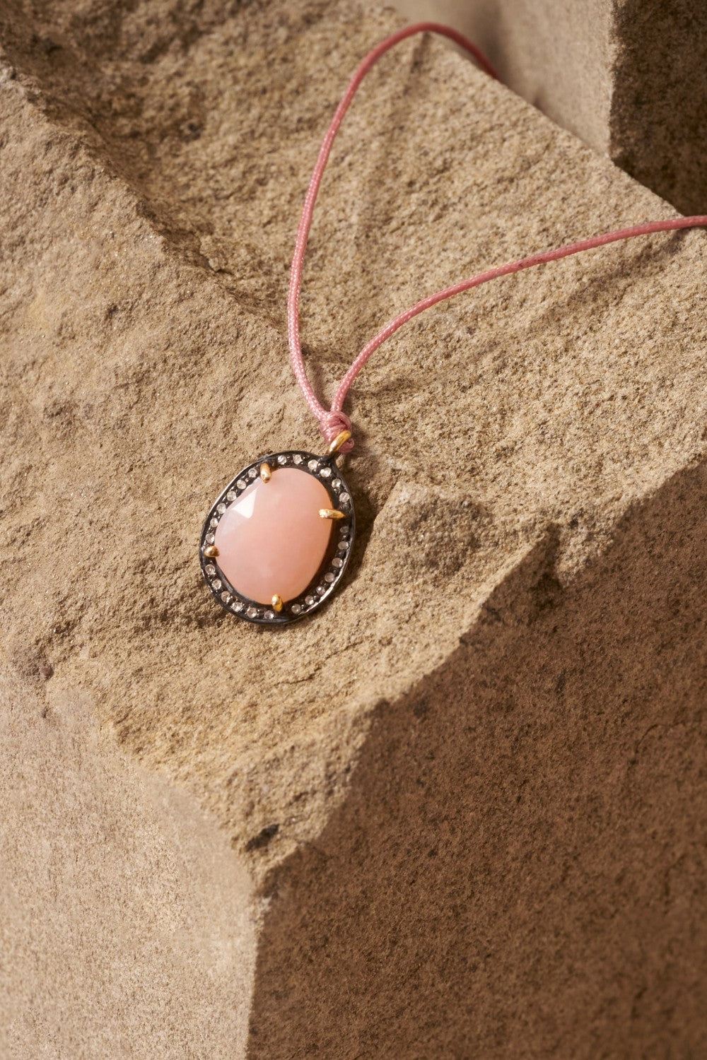 pink opal and diamond necklace on a rock